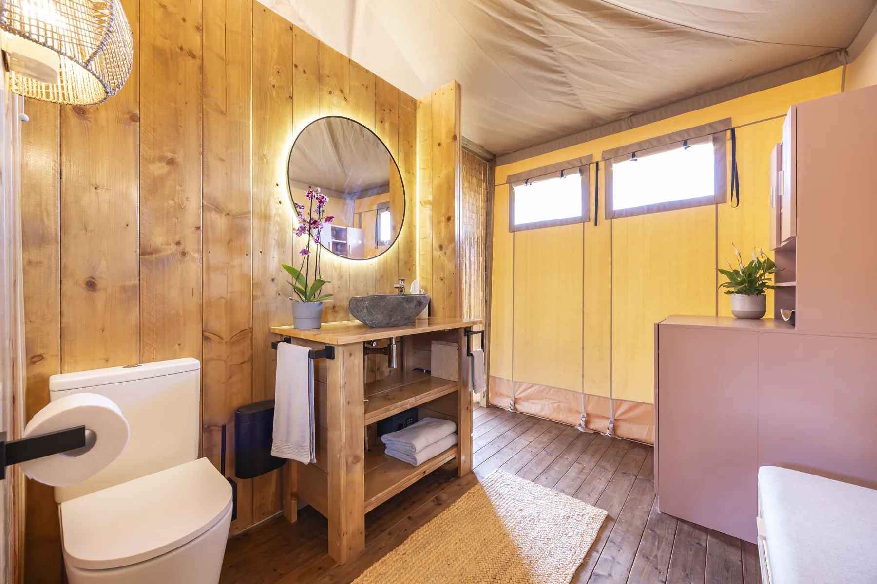 Badkamer met ronde spiegel en wastafel op een houten meubel